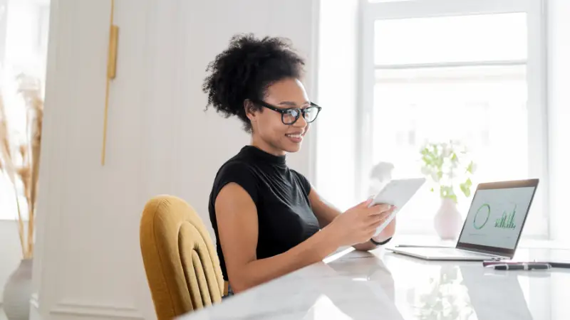 Entrepreneur reviewing data on a tablet and laptop, demonstrating strong analytical skills in a modern office
