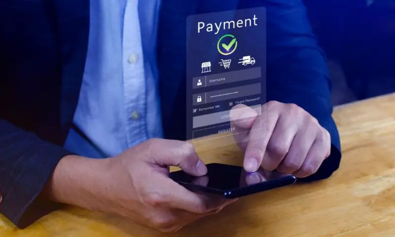 A person in a suit uses a smartphone with a transparent digital payment interface displayed