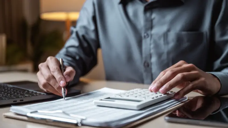 Entrepreneur reviewing financial statements with a calculator, focused on financial analysis and cash flow planning