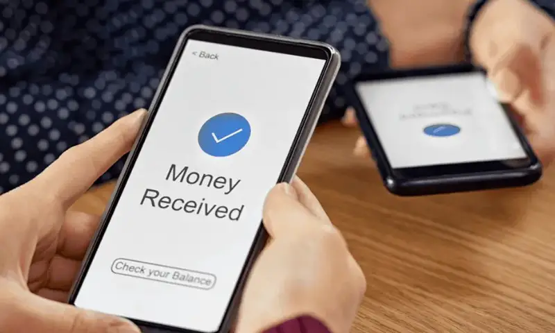 Close-up of two hands holding smartphones; one screen shows "Money Received" with a checkmark